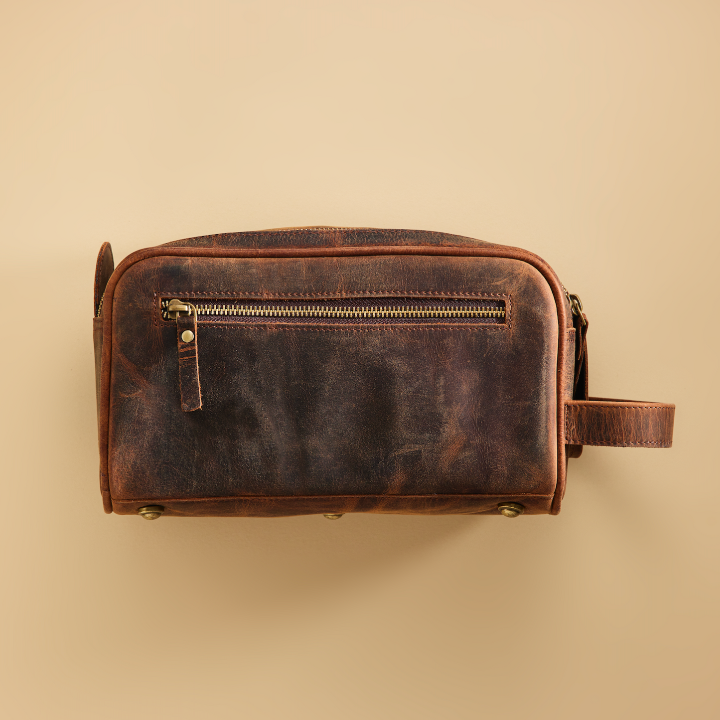 Brown leather toiletry bag on a beige background
