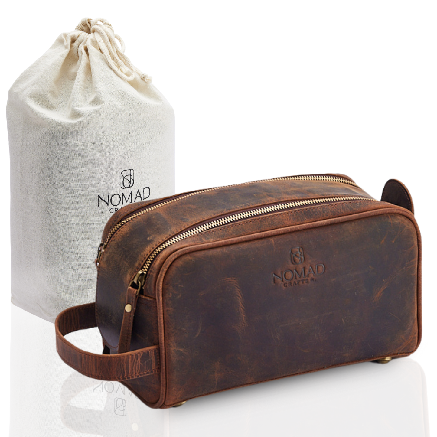 Brown leather toiletry bag with gold zipper and matching drawstring bag on a white background, featuring 'Nomad' branding.