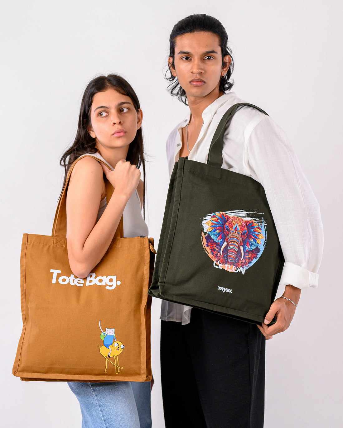 Two people holding tote bags with visible branding against a plain background