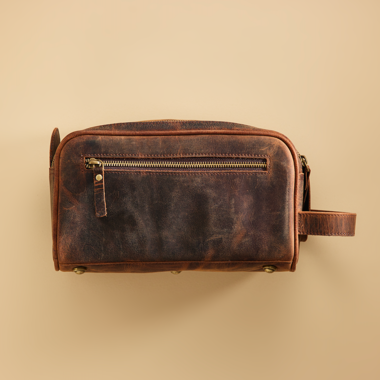 Brown leather toiletry bag on a beige background