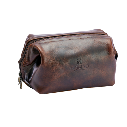 Brown leather toiletry bag with 'Nomad' branding on a white background
