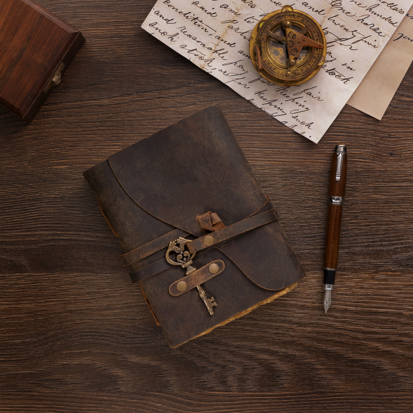 Brown leather journal with decorative strap on a wooden surface with a pen and paper.