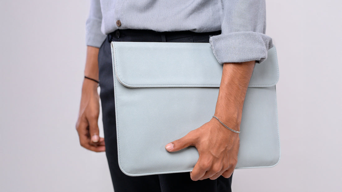 Person holding a light blue clutch bag against a plain background